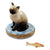 Siamese cat with blue eyes sitting on a shelf next to a fish bowl 