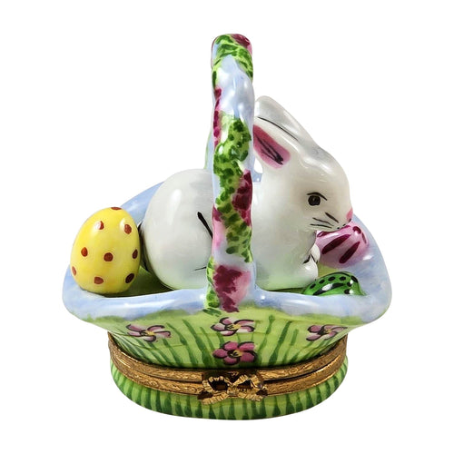 White rabbit figurine with long ears and pink nose sitting in a colorful Easter basket surrounded by wisteria flowers and greenery Limoges box