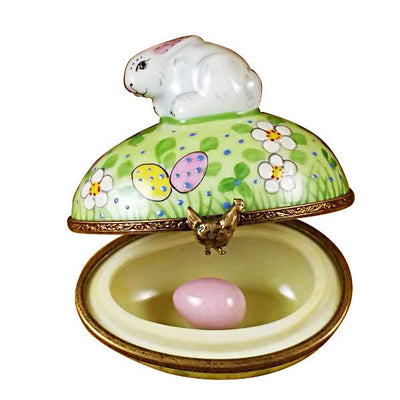 Rabbit sitting on a decorated Easter egg surrounded by spring flowers